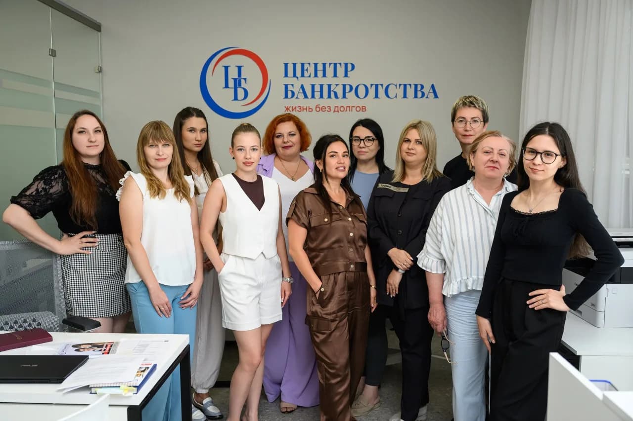 Команда «Центра Банкротства» у стены с логотипом